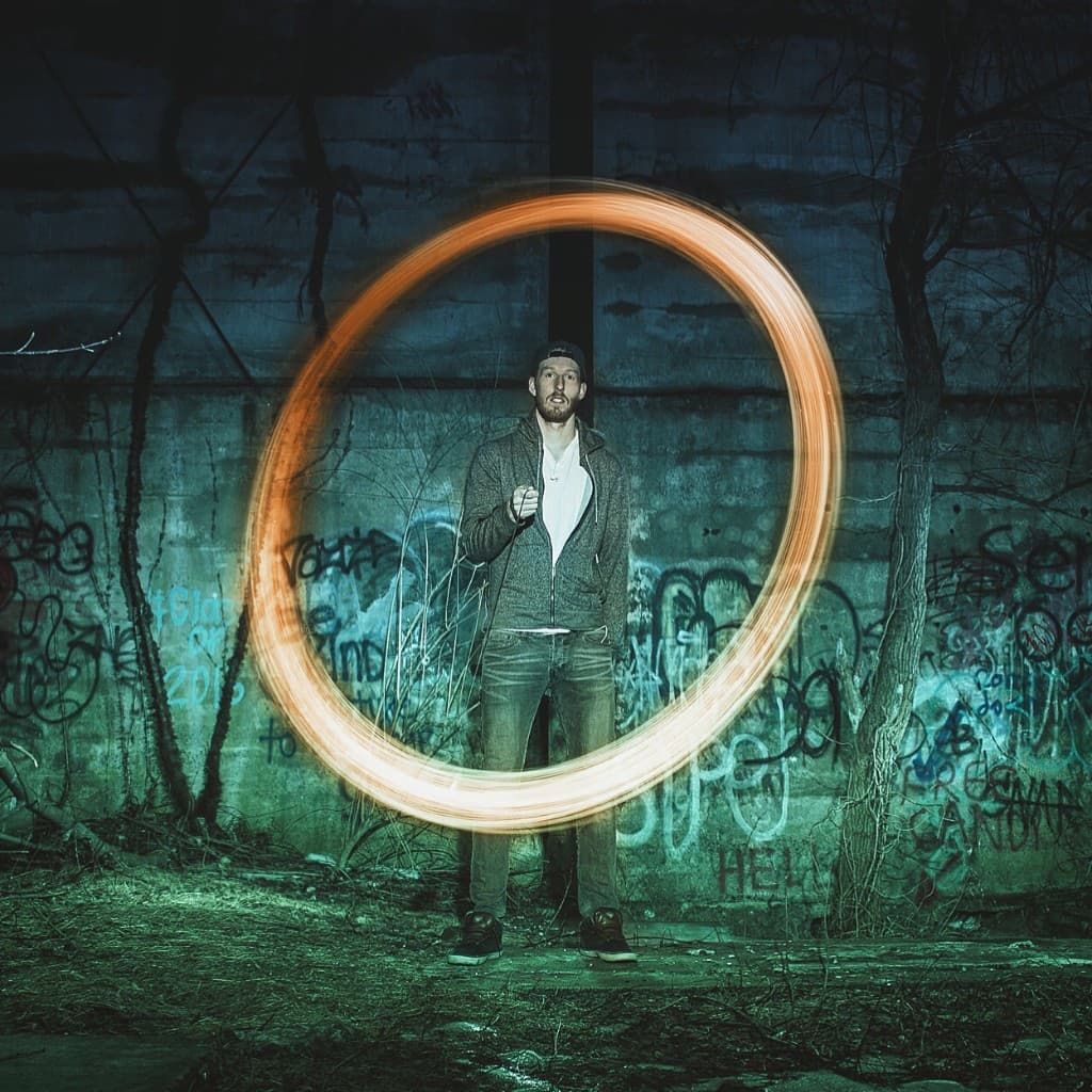 Adlay standing against a graffiti wall with a spinning ring of light